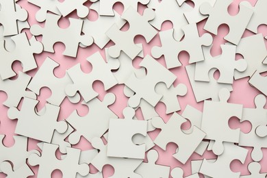 Photo of White puzzle pieces on pink background, top view