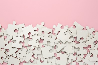 Photo of White puzzle pieces on pink background, top view. Space for text