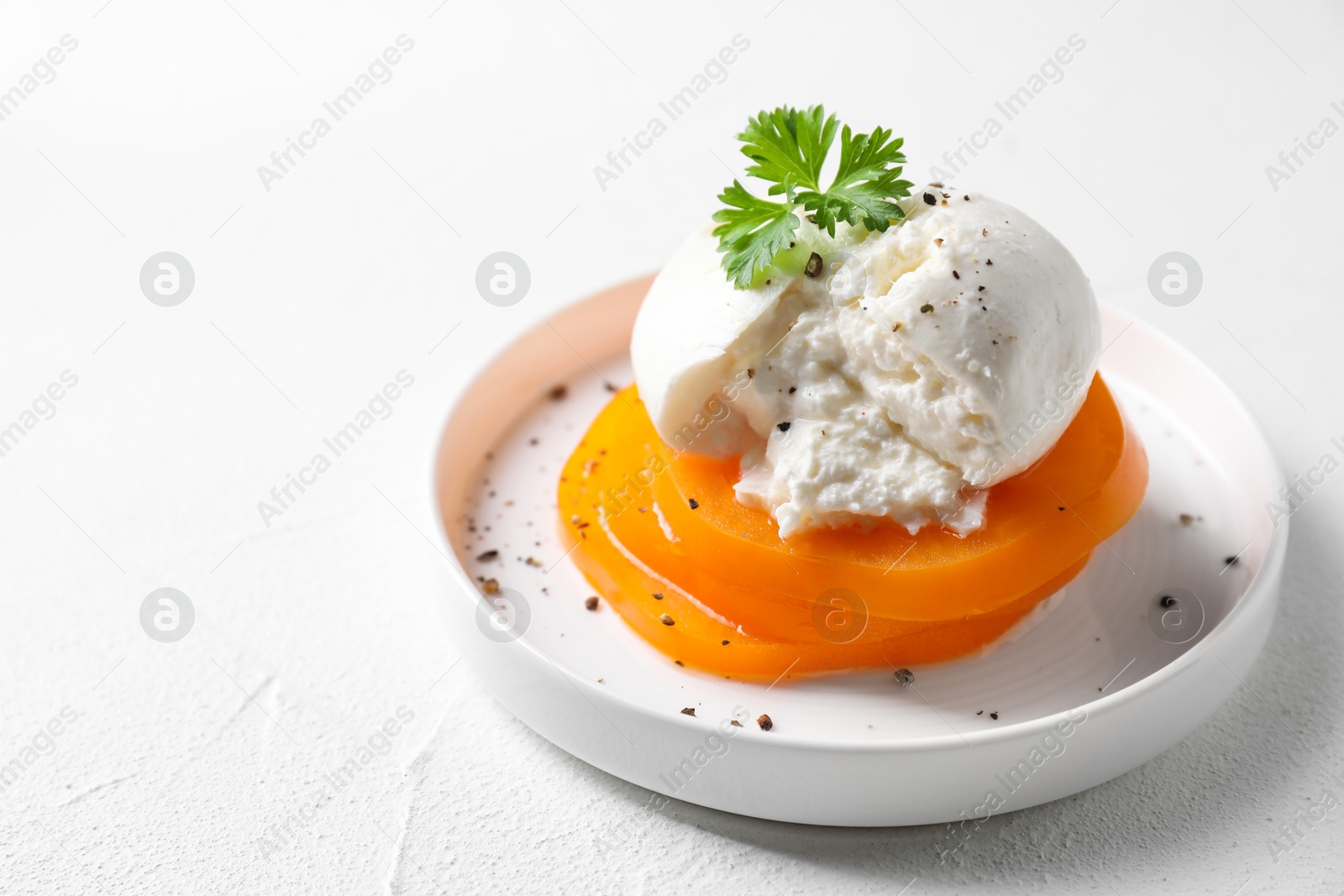 Photo of Delicious burrata cheese, tomato and parsley on white table, closeup. Space for text