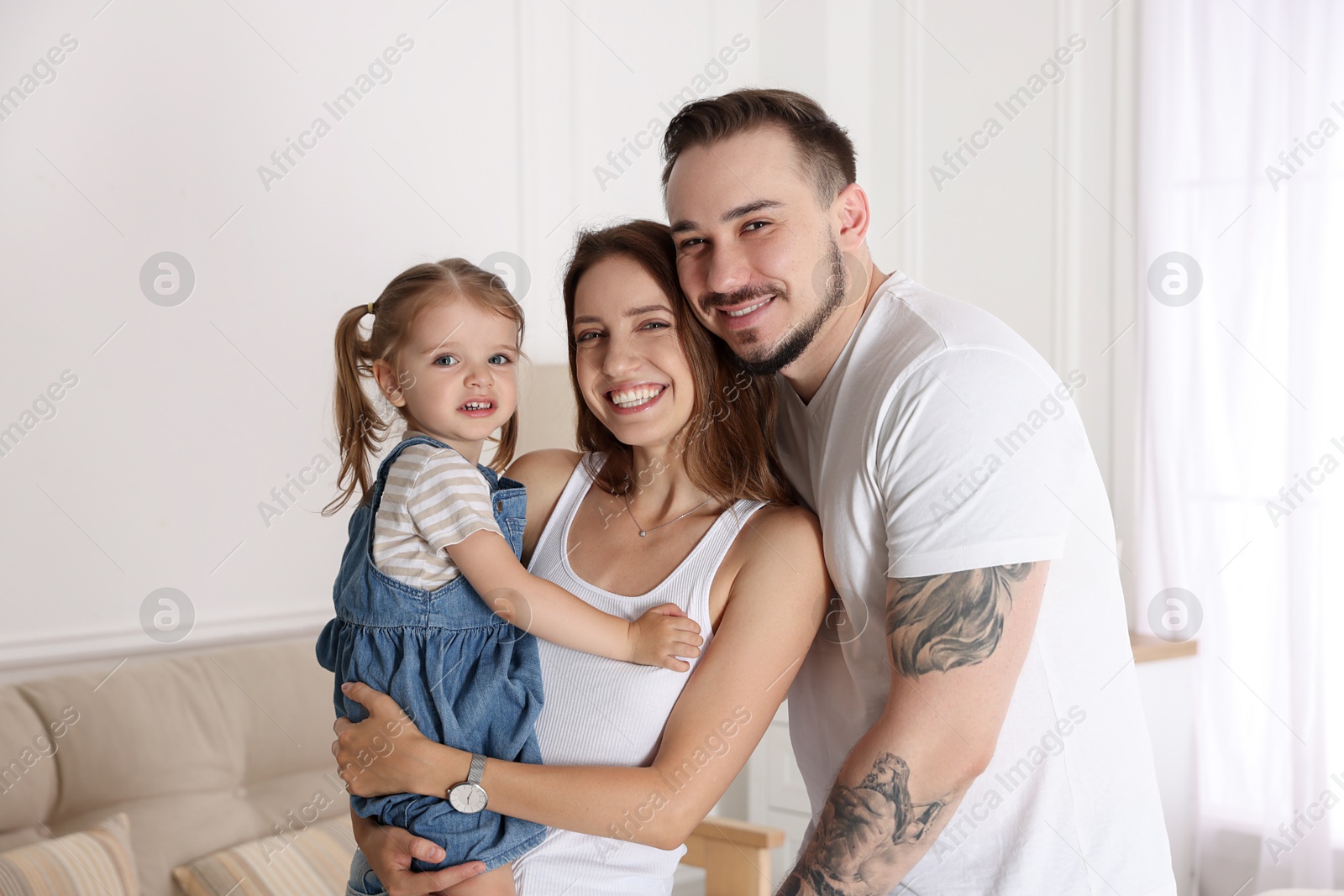 Photo of Happy family. Parents and their cute little daughter at home