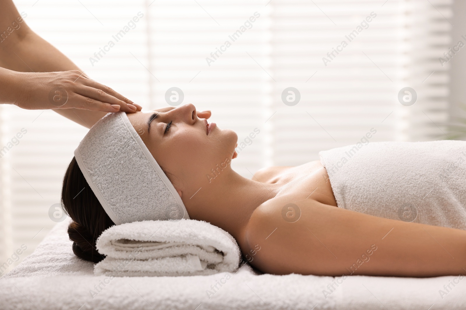 Photo of Attractive woman enjoying face massage in spa salon