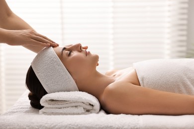 Photo of Attractive woman enjoying face massage in spa salon