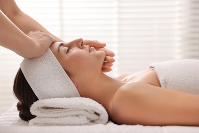 Photo of Attractive woman enjoying face massage in spa salon