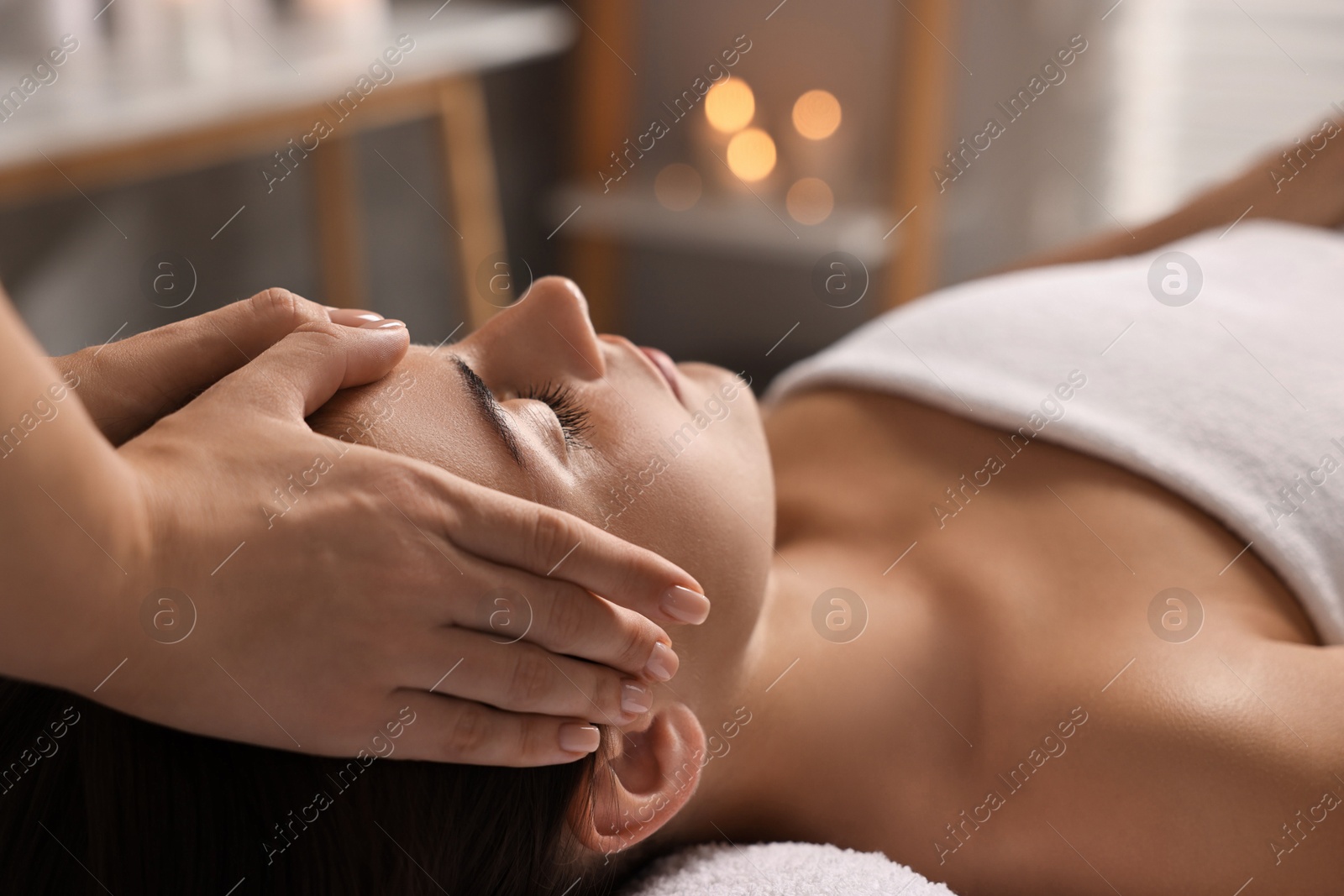 Photo of Attractive woman enjoying face massage in spa salon, closeup