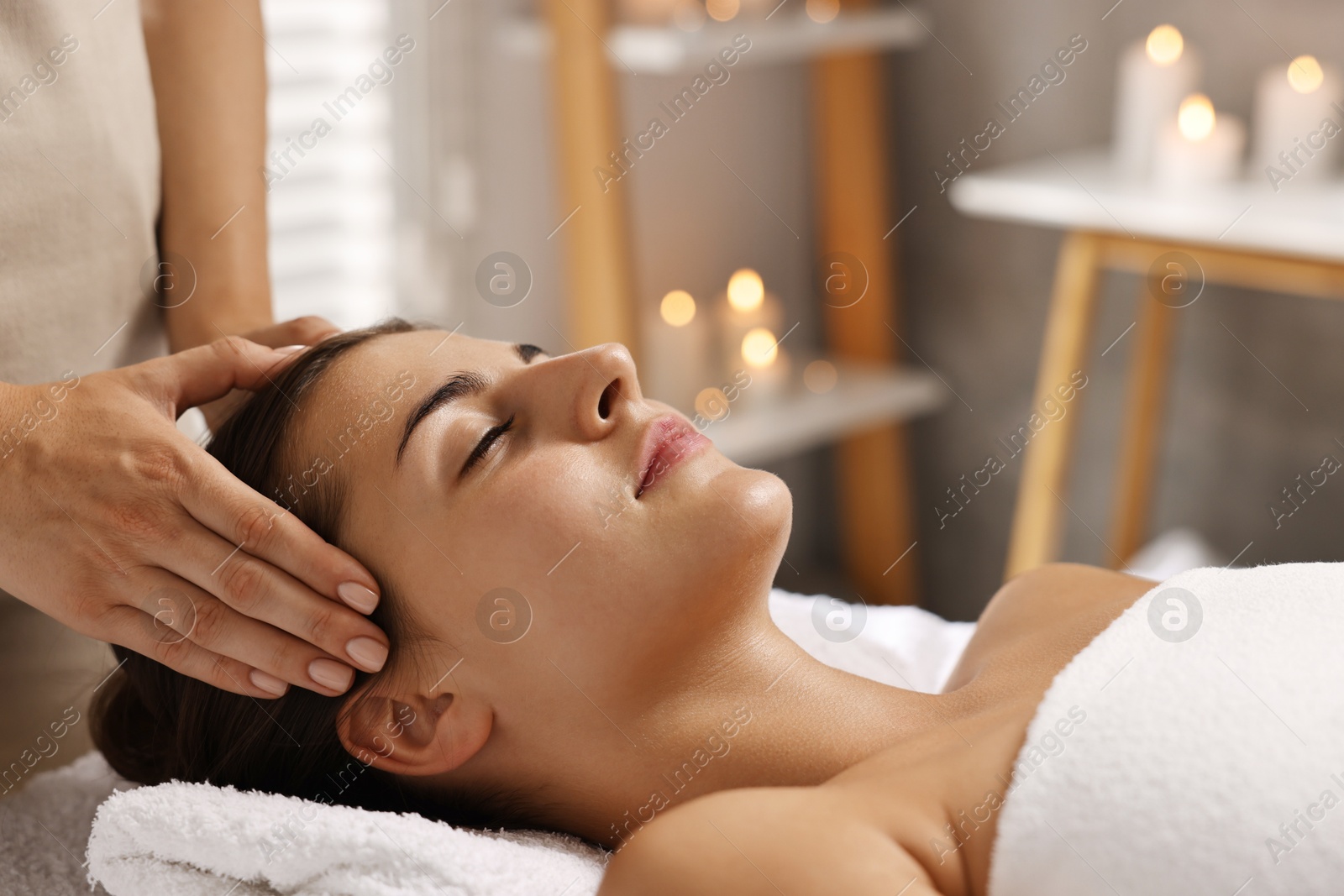 Photo of Attractive woman enjoying face massage in spa salon, closeup