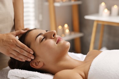 Attractive woman enjoying face massage in spa salon, closeup