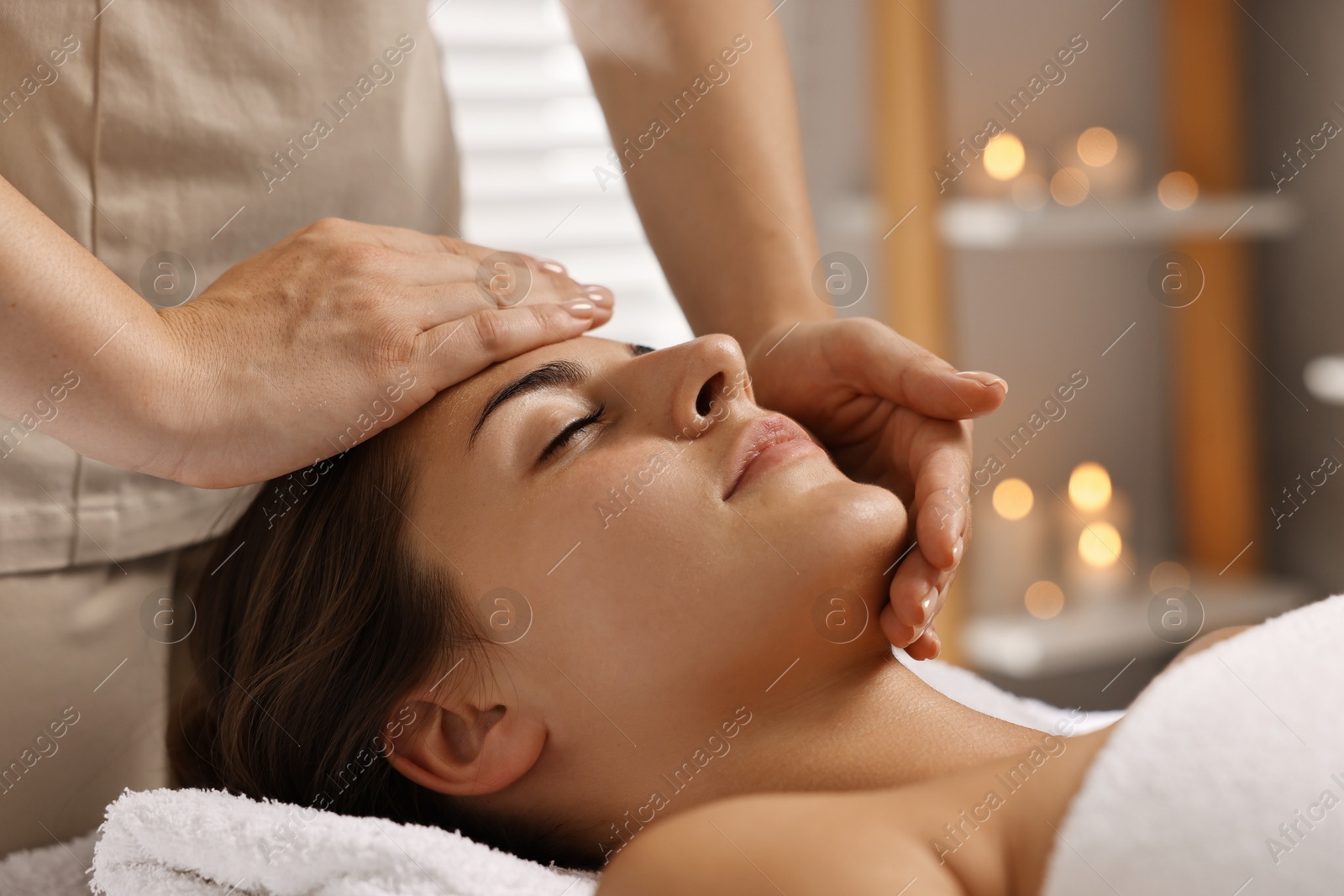 Photo of Attractive woman enjoying face massage in spa salon, closeup