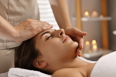 Attractive woman enjoying face massage in spa salon, closeup