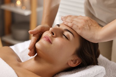 Attractive woman enjoying face massage in spa salon, closeup