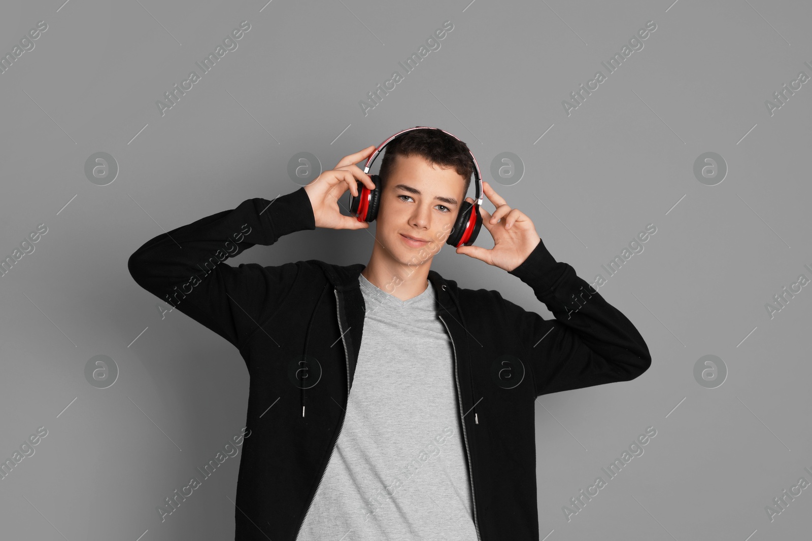 Photo of Portrait of teenage boy with headphones on grey background