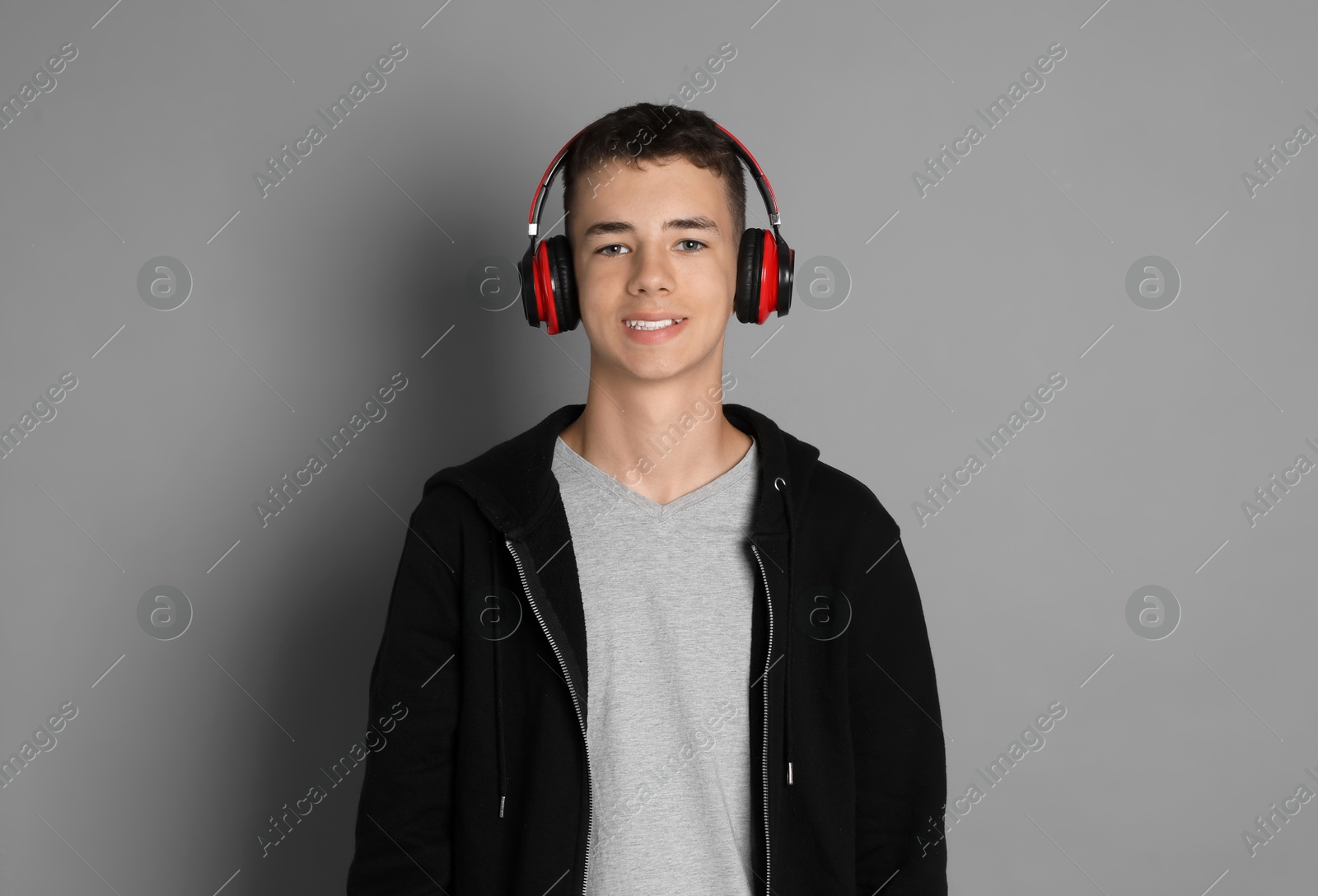 Photo of Portrait of teenage boy with headphones on grey background