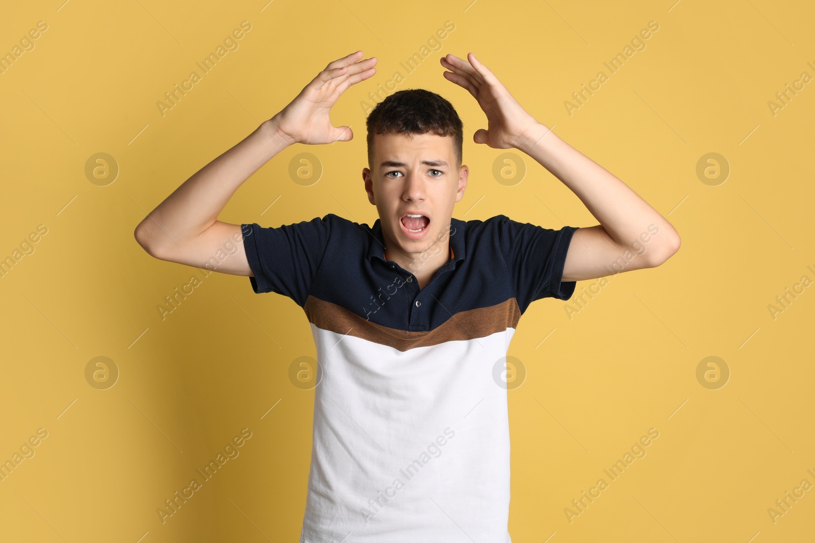 Photo of Portrait of angry teenage boy on yellow background