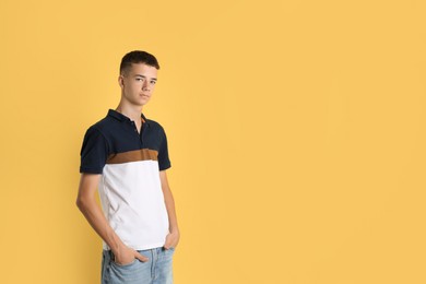 Portrait of teenage boy on yellow background, space for text