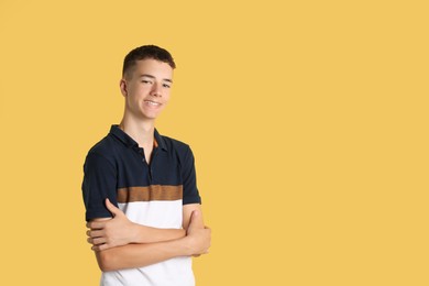 Portrait of teenage boy on yellow background, space for text