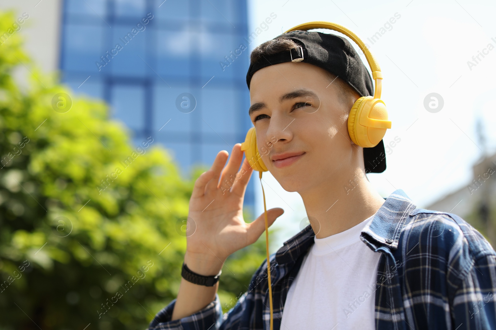 Photo of Portrait of teenage boy with headphones outdoors. Space for text