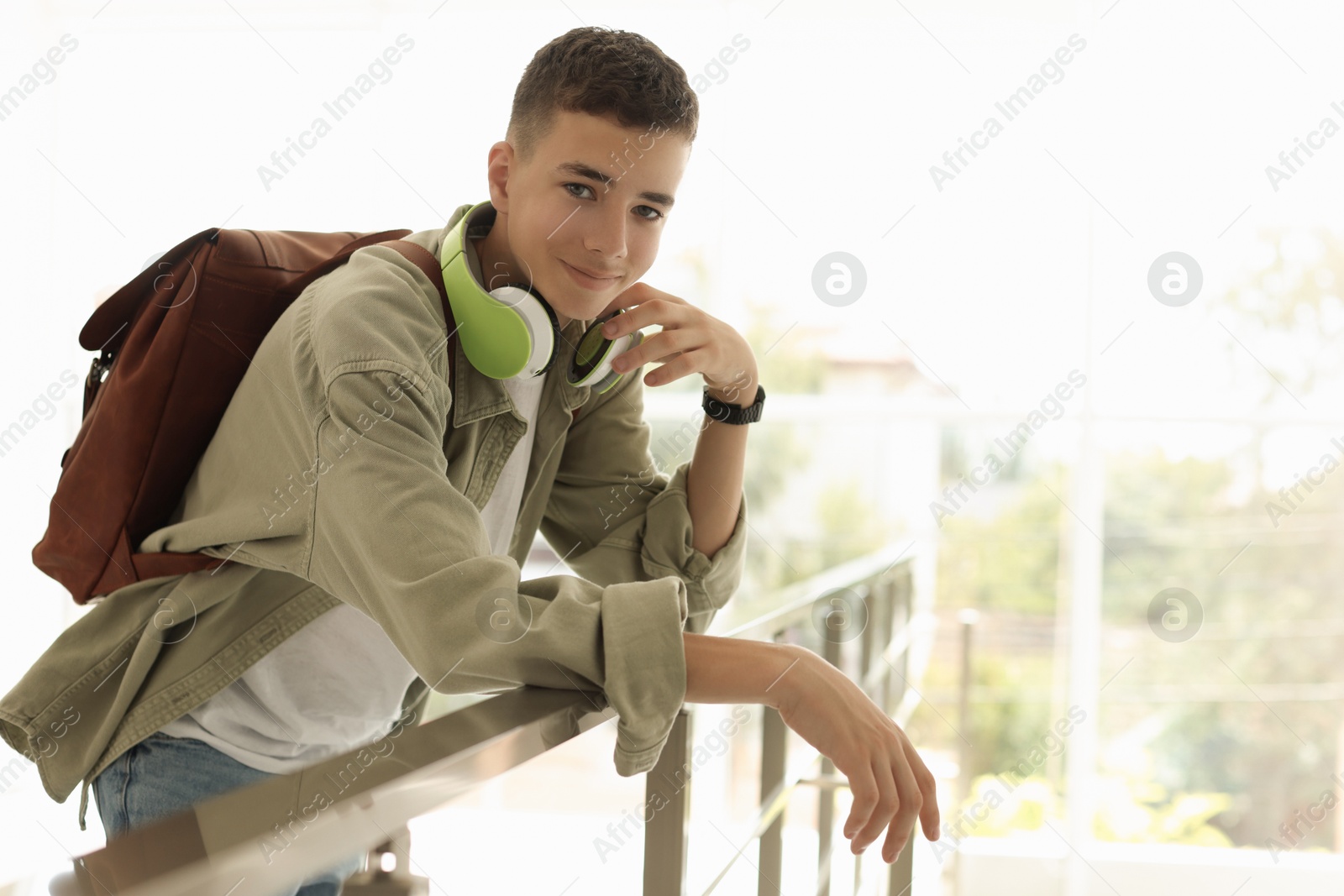 Photo of Portrait of teenage boy near railings indoors. Space for text