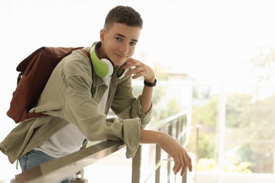 Portrait of teenage boy near railings indoors. Space for text