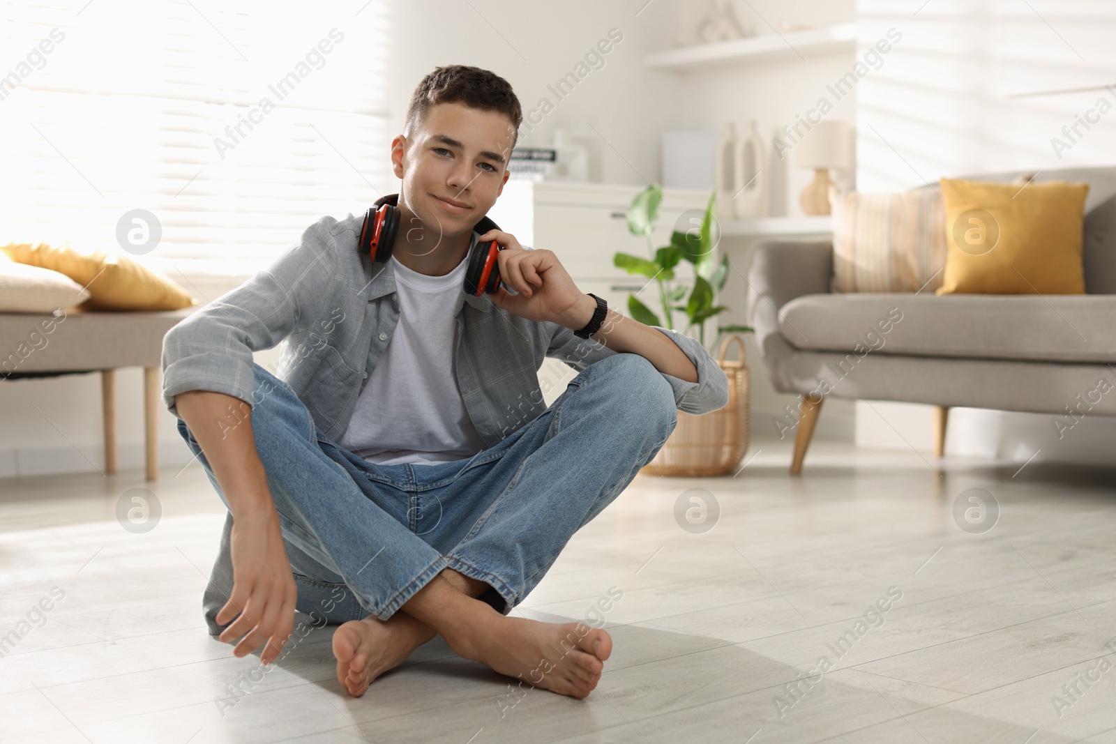 Photo of Full length portrait of teenage boy sitting on floor at home. Space for text