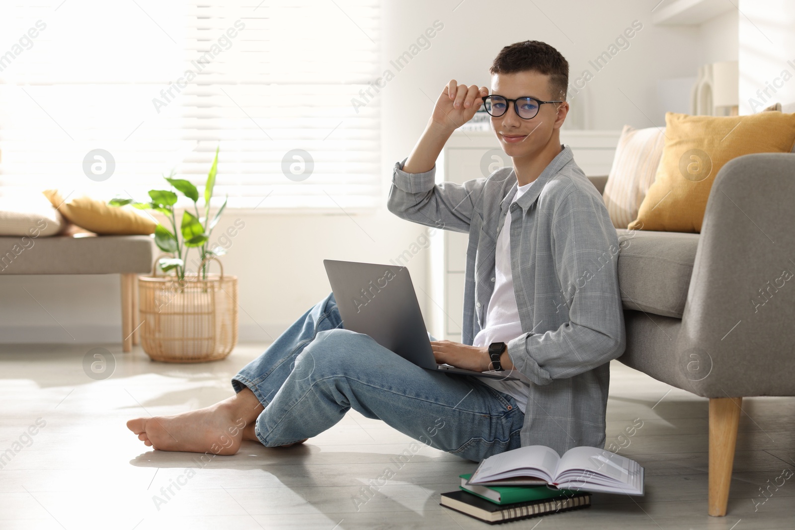 Photo of Full length portrait of teenage boy studying with laptop at home. Space for text