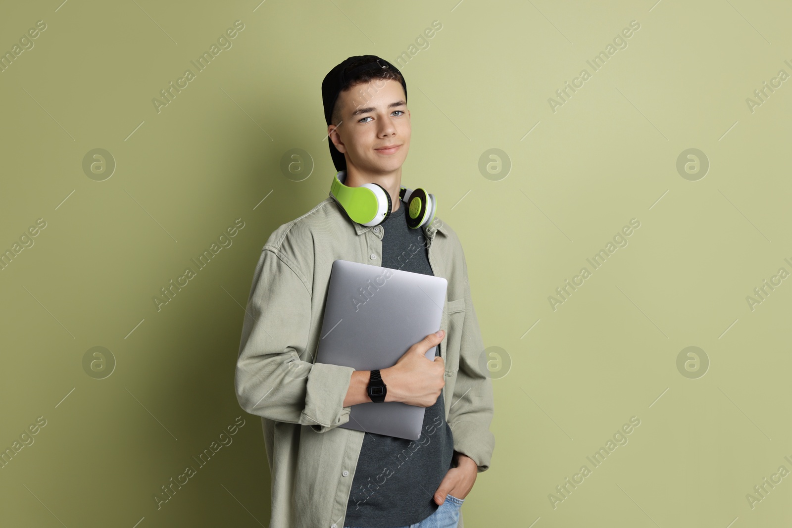 Photo of Portrait of teenage boy with laptop on green background