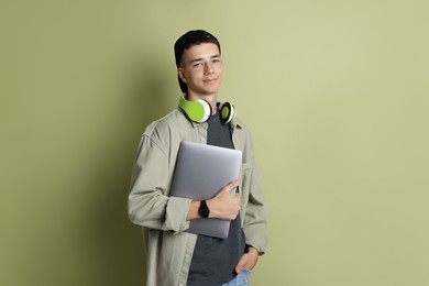 Portrait of teenage boy with laptop on green background