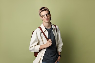 Portrait of teenage boy with backpack on green background