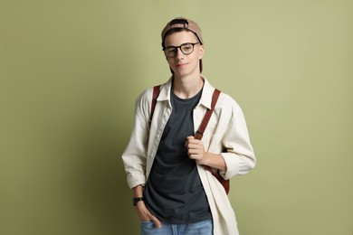 Portrait of teenage boy with backpack on green background