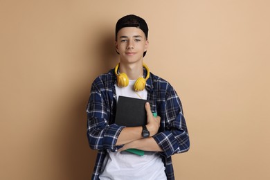 Portrait of teenage boy with books on dark beige background