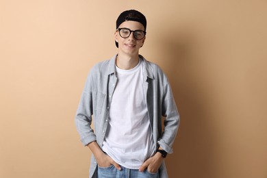 Portrait of smiling teenage boy on dark beige background