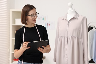 Photo of Fashion designer with clipboard working in workshop