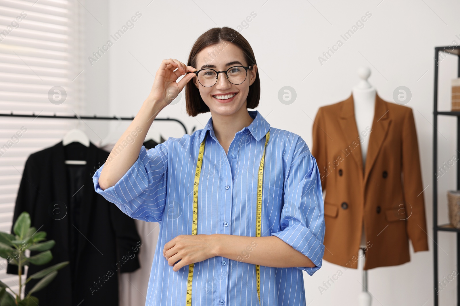 Photo of Fashion designer with measuring tape in workshop