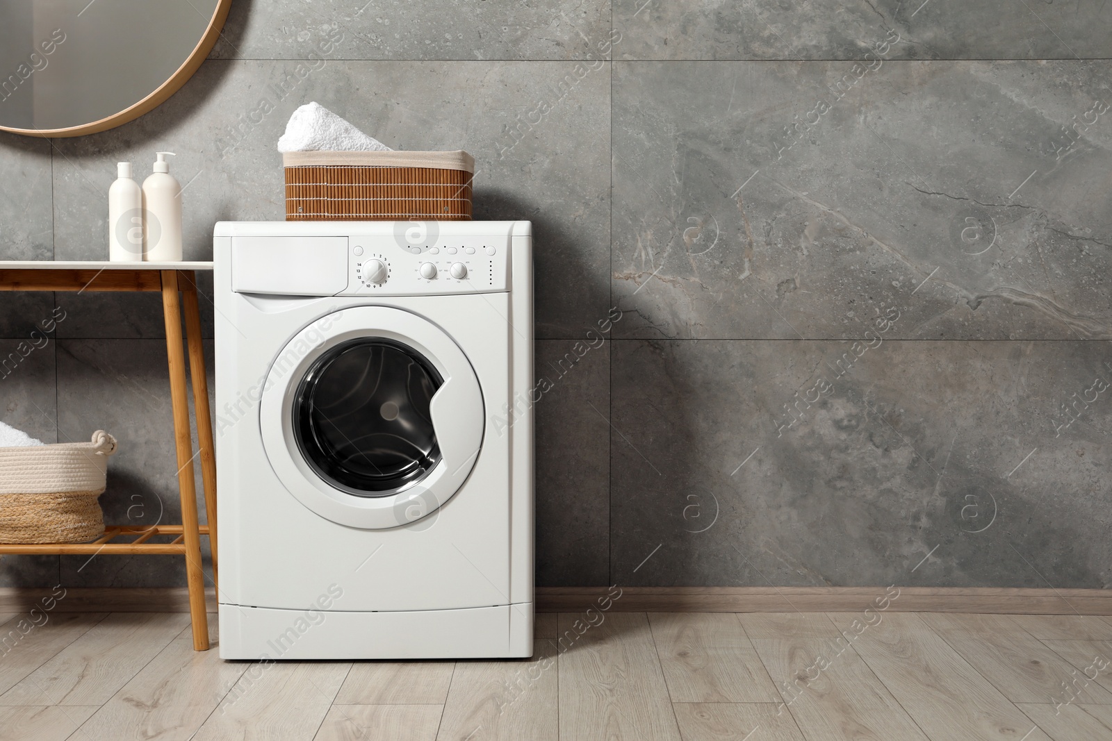 Photo of Washing machine, baskets with laundry and storage bench indoors, space for text