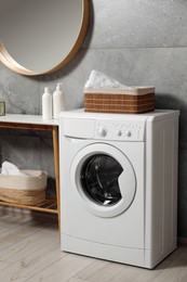 Photo of Washing machine, baskets with laundry and storage bench indoors