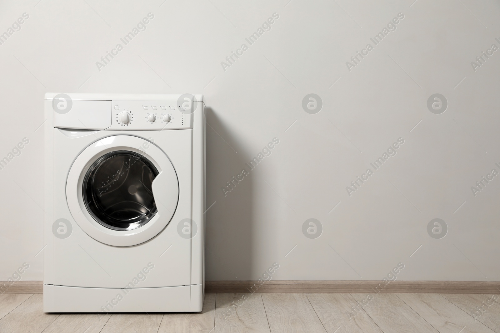 Photo of Washing machine near white wall indoors, space for text