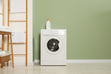 Photo of Washing machine, towels and detergent in laundry room