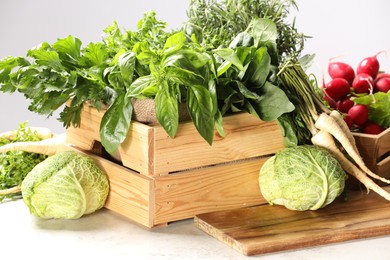 Photo of Different fresh herbs, cabbages and radishes on white table