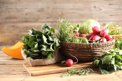 Photo of Different fresh herbs, cabbages, radishes and pumpkin on wooden table