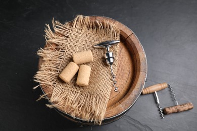 Photo of Different corkscrews, corks and wooden barrel on grey table, above view