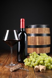 Photo of Corkscrew, corks, bottle of wine, glass, grapes and barrel on wooden table