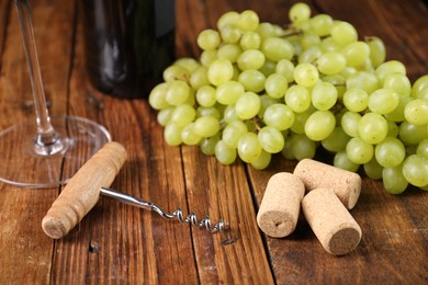 Photo of Corkscrew, corks and grapes on wooden table, closeup