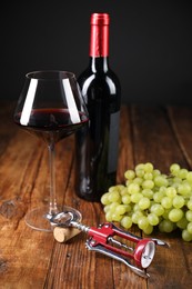 Photo of Wing corkscrew, cork, bottle of wine, glass and grapes on wooden table