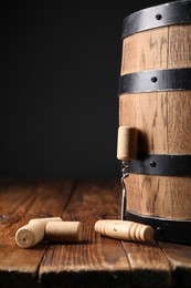 Photo of Corkscrew, corks and barrel on wooden table