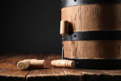 Photo of Corkscrew, corks and barrel on wooden table, closeup