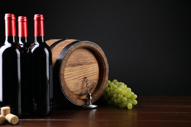 Photo of Corkscrew with metal handle, corks, grapes, bottles of wine and barrel on wooden table. Space for text