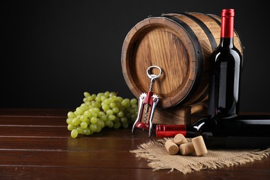 Wing corkscrew, corks, bottles of wine, grapes and barrel on wooden table