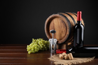 Photo of Wing corkscrew, corks, bottles of wine, grapes and barrel on wooden table