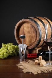 Photo of Wing corkscrew, corks, bottle of wine, glass, grapes and barrel on wooden table