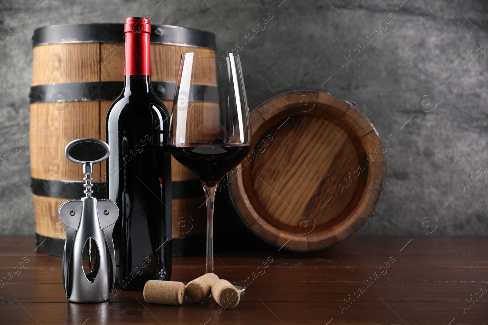 Photo of Wing corkscrew, corks, bottle of wine, glass and barrels on wooden table