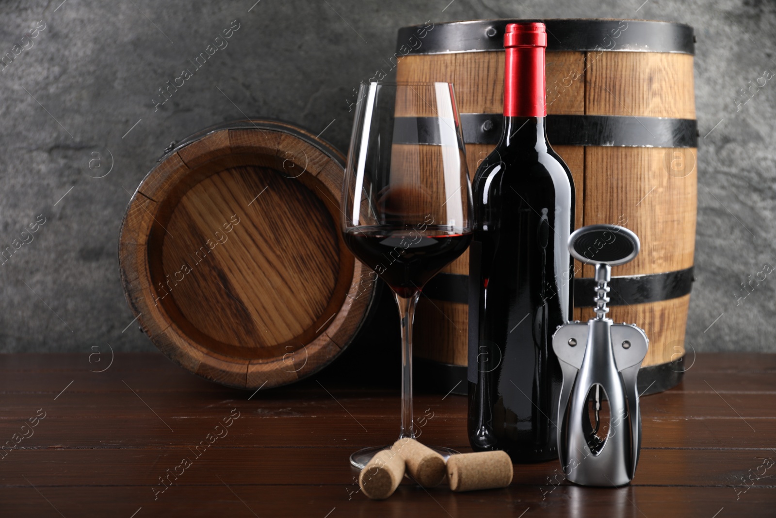 Photo of Wing corkscrew, corks, bottle of wine, glass and barrels on wooden table