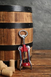 Photo of Wing corkscrew, corks and wooden barrel on table